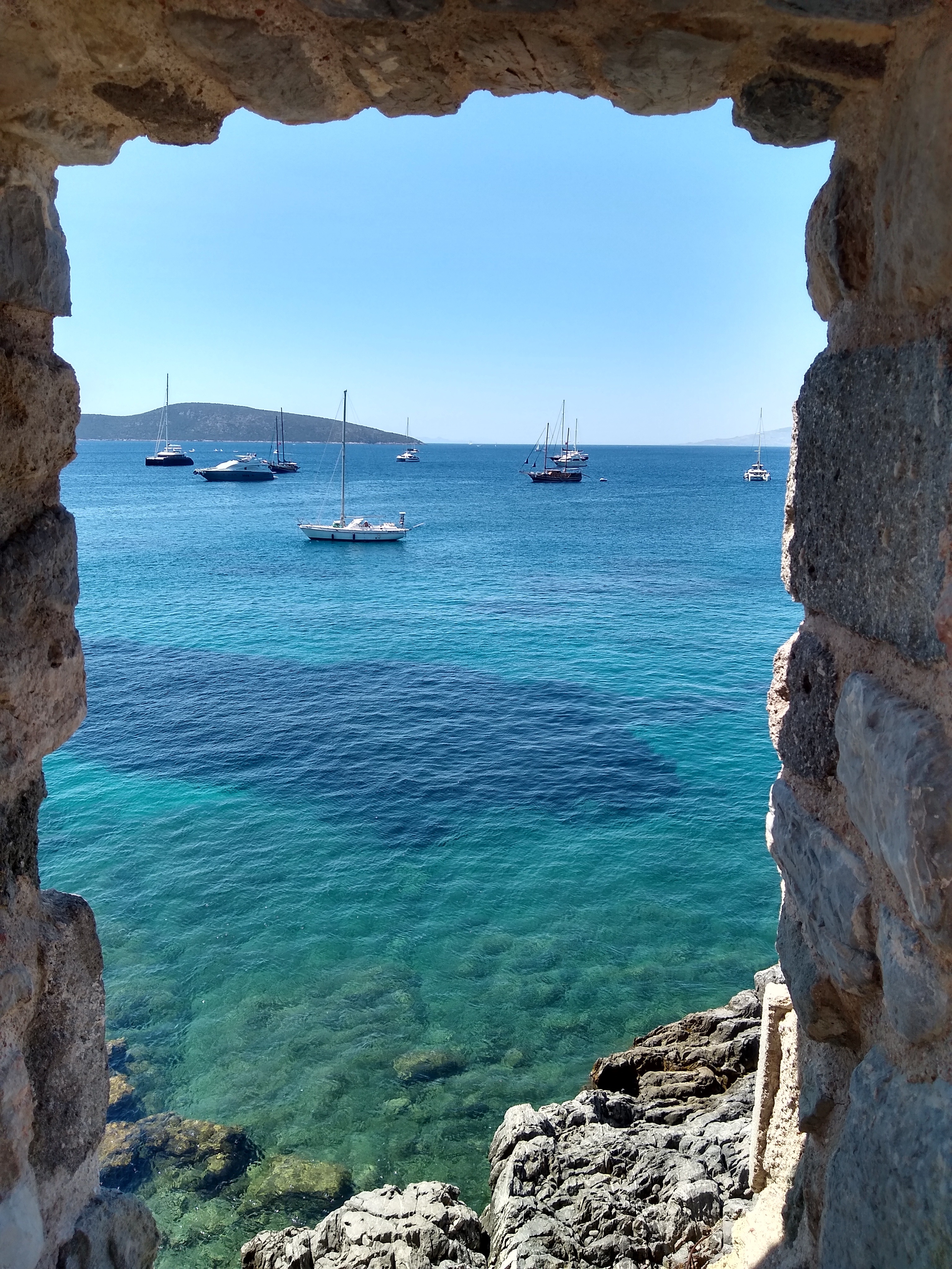 Boats and blue water viewed through an opening in the castle wall
