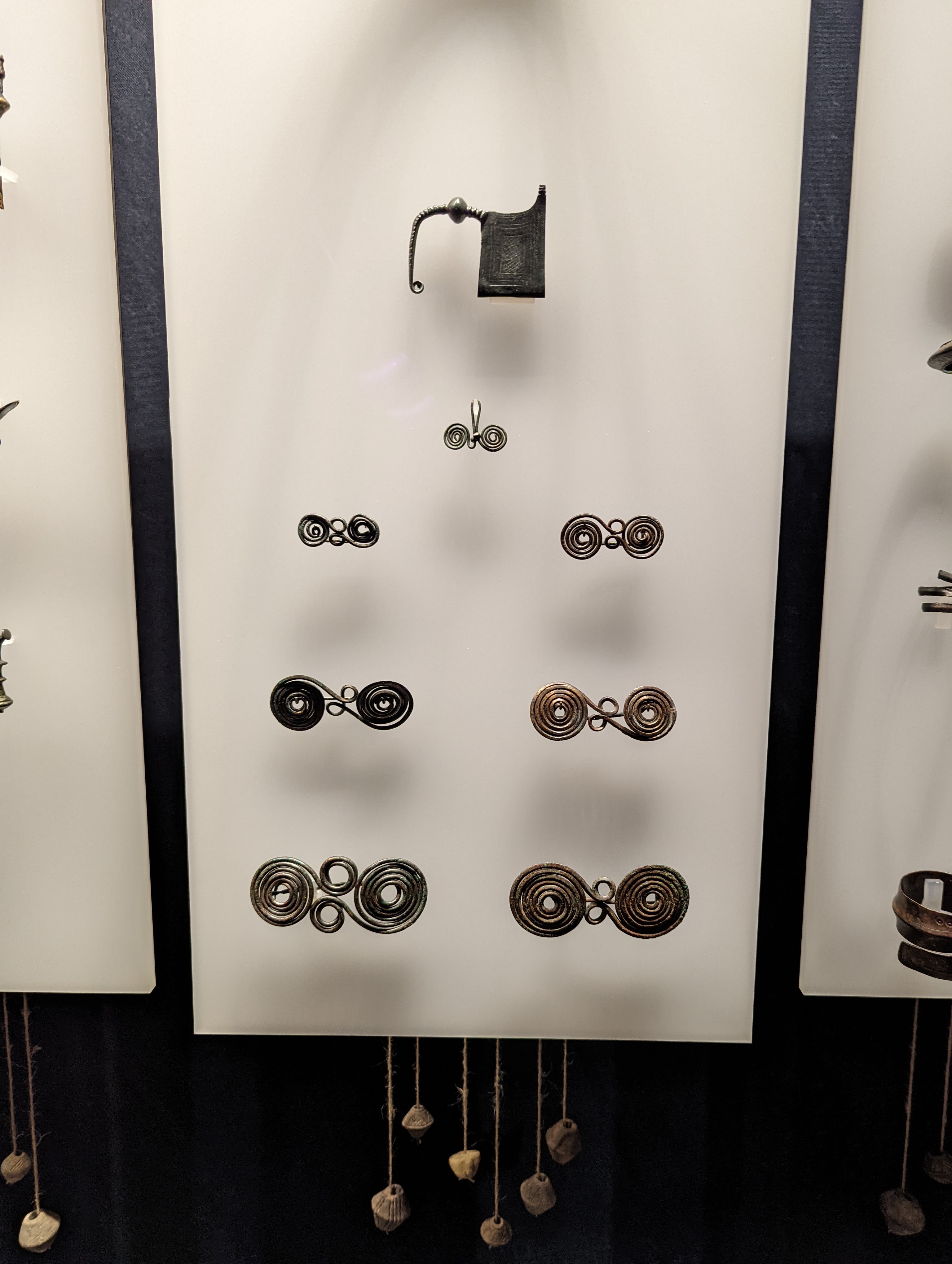 Ancient bronze dress fasteners, specifically featuring spectacle fibulae (brillenfibel) and early safety-pin brooches.