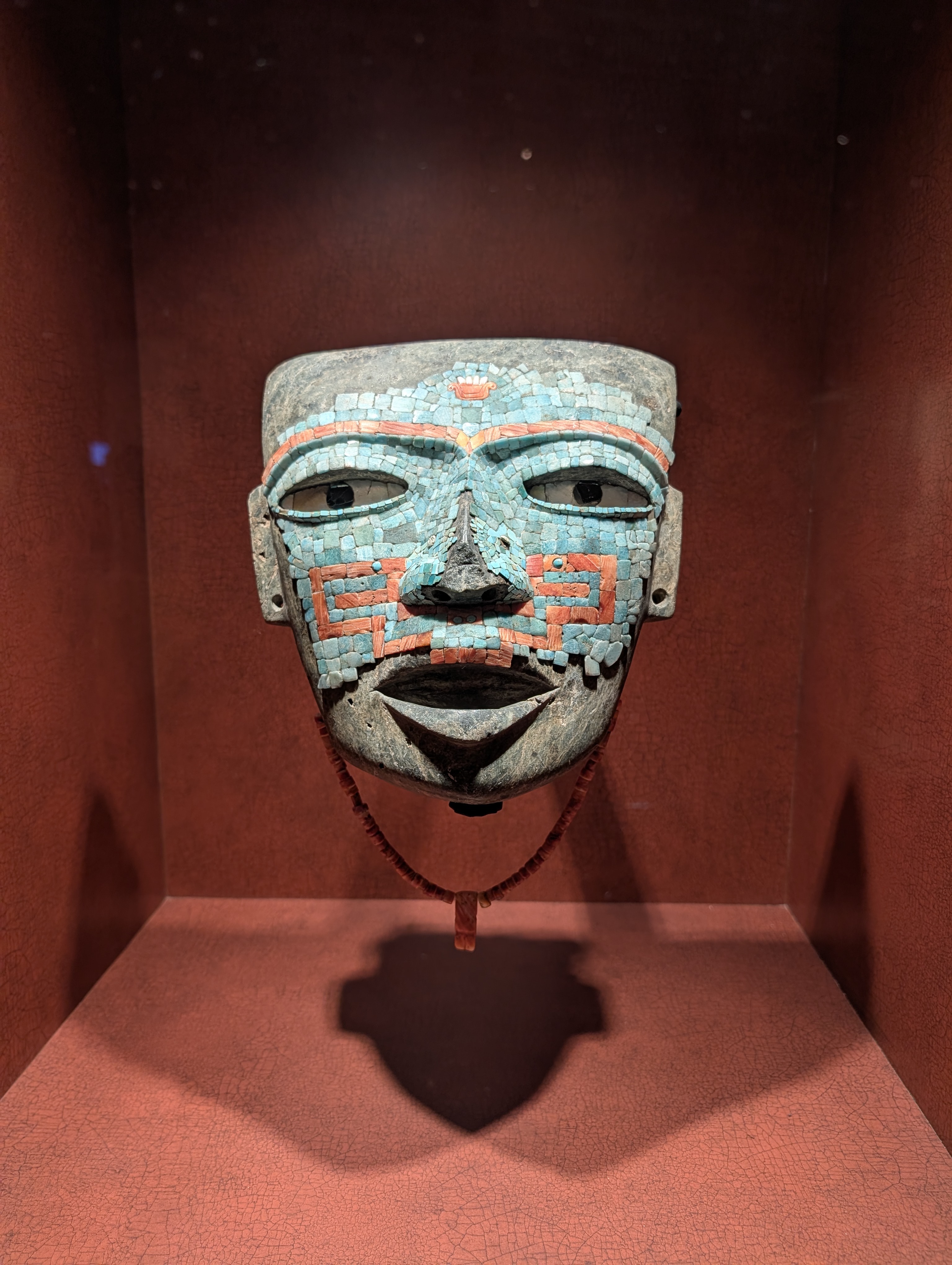 A stone mosaic funerary / ceremonial mask inlaid with a turquoise and shell mosaic in the style associated with Teotihuacán and later Mixtec / Aztec-period mosaic work.