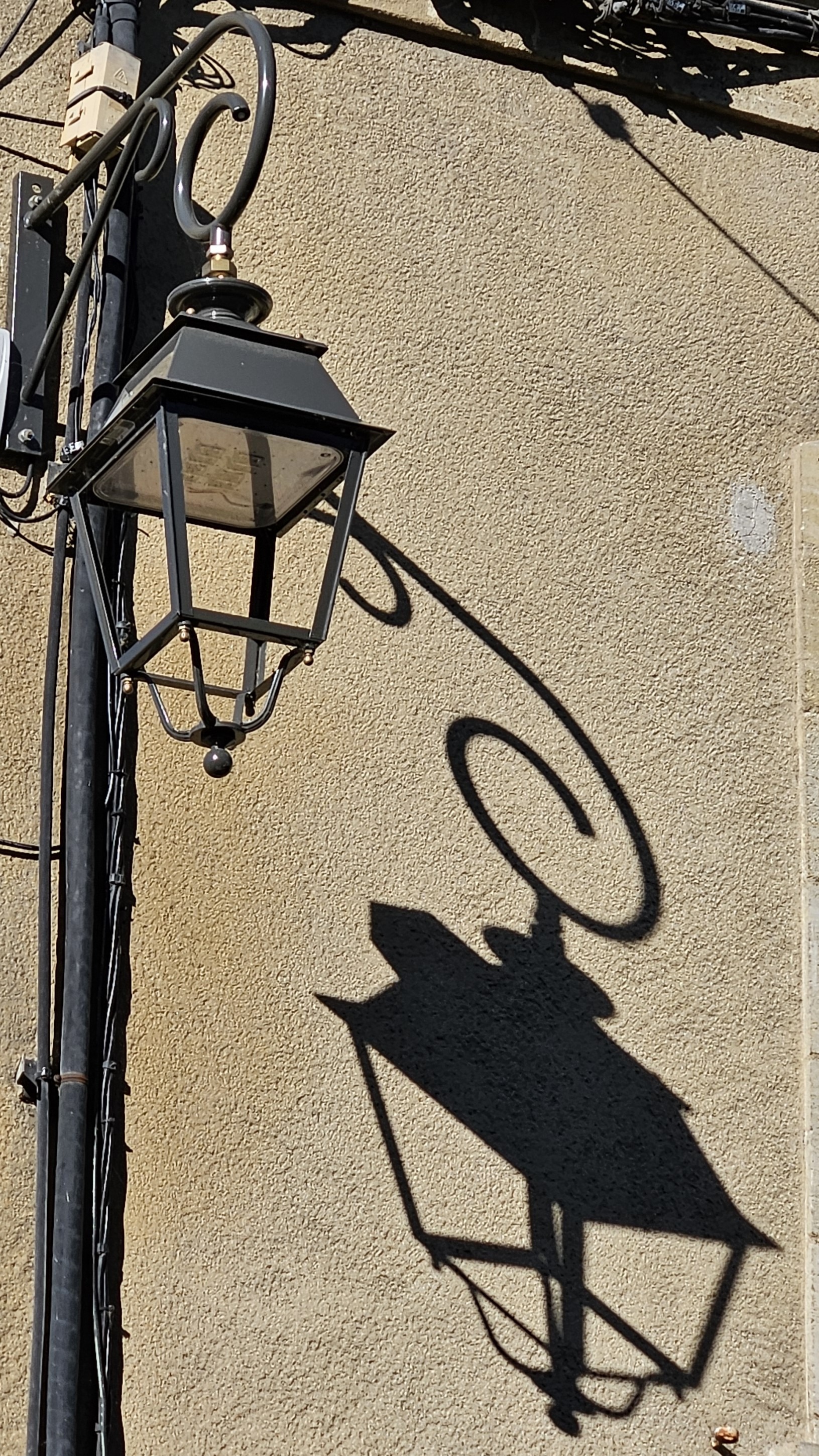 Lamp and its shadow against a stucco wall