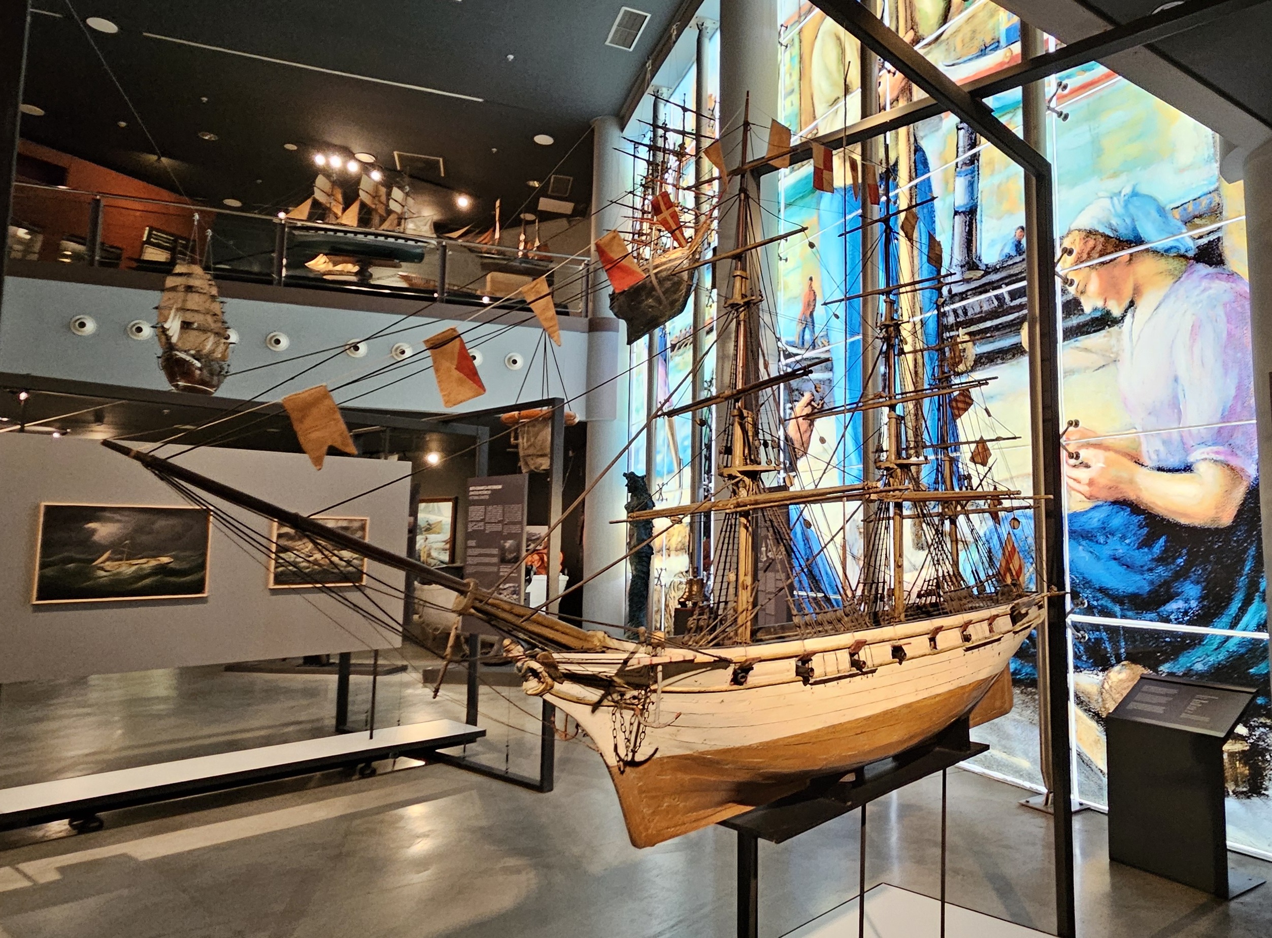 Ship replica with glass mural and other museum displays in background